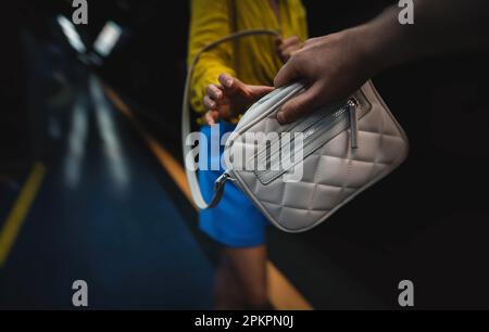 Der Dieb stiehlt einer Frau in der U-Bahn eine Tasche. Stockfoto