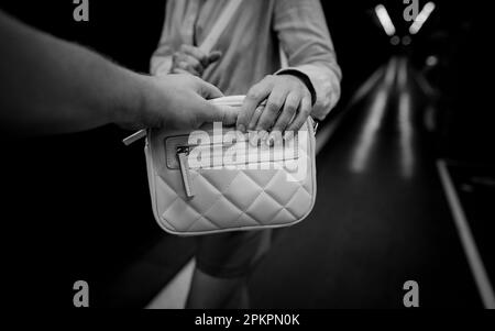 Der Dieb stiehlt einer Frau in der U-Bahn eine Tasche. Stockfoto