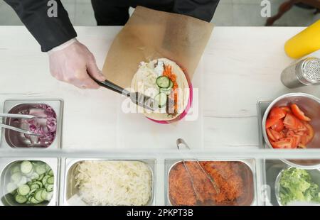 Kochen Sie Pita-Sandwich mit frischem Gemüse in einer griechischen Restaurantküche. Stockfoto