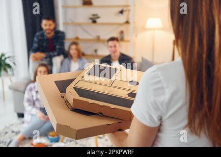 Ich sitze auf dem Sofa. Eine Gruppe von Freunden feiert zusammen drinnen Stockfoto