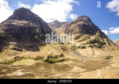 Die imposanten Gipfel von Bidean Nam Bian erheben sich an einem klaren Frühlingstag im schottischen Hochland über dem Heideland von Glen Coe Stockfoto