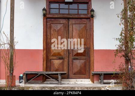 Ein traditionelles Dorfhaus aus Holz am Schwarzen Meer mit zwei Türen und Holzbänken auf beiden Seiten des Eingangs. Stockfoto