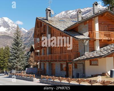 Großes Gebäude aus Holz und Stein mit Balkon und Schieferdach mit mehreren Kaminen in Cogne, Gran Paradiso Nationalpark in der Region Aosta Valley, Italien Stockfoto