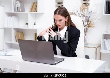 Frau im Büro, die auf den Laptop-Bildschirm schaut. Stockfoto