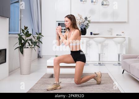 Fitnessfrau, die zu Hause Ausfallübungen macht. Stockfoto