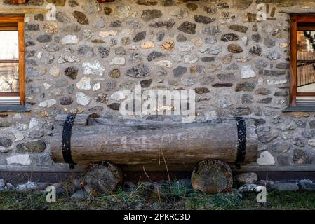 Ein alter Trinkbrunnen aus einem Holzstamm auf einem Bauernhaus in den Schweizer Alpen Stockfoto