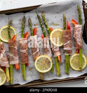 In Prosciutto verpackte Spargelspieße, bereit für den Ofen. Stockfoto
