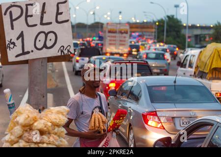 Die Bewohner von Complexo da Mare, einem riesigen Favelas-Netz, das sich neben der Linha Vermelha ( Rote Linie ) befindet, der Hauptautobahn vom internationalen Flughafen Rio de Janeiro zum Stadtzentrum, arbeiten während der Hauptverkehrszeiten an der Schnellstraße als Straßenverkäufer. Stockfoto