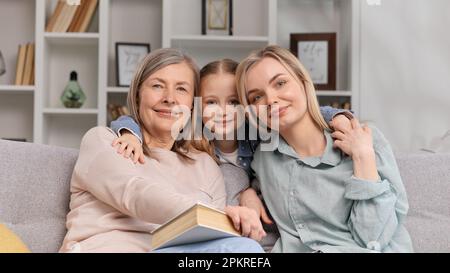 Die kleine Enkelin umarmt eine 60-jährige Großmutter und junge Mutter, zeigt Liebe am Muttertag und schaut in die Kamera. Ein Porträt von Familienliebe Stockfoto