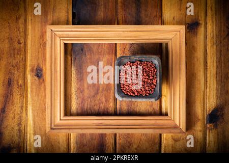 Achiotkorn in einem Becher auf Holzhintergrund Stockfoto