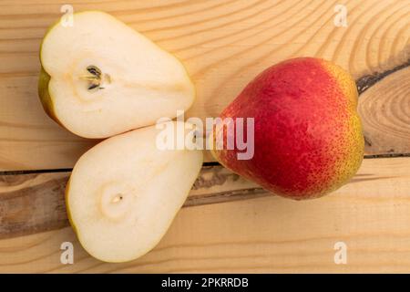 Zwei Hälften und eine ganze Bio-Birne, Nahaufnahme, auf einem Holztisch, Draufsicht. Stockfoto