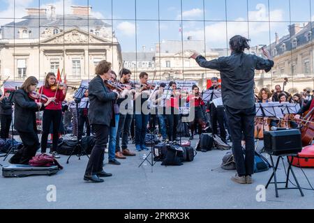 Die SDAMP-CGT-Mitglieder treten am 9. April 2023 auf dem Place du Palais Royal in Paris, Frankreich, während eines Konzerts eines Symphonieorchesters auf, um gegen eine Rentenreform zu protestieren, wie sich der Staatsrat in Spiegeln widerspiegelt. Musiker interpretierten insbesondere Werke von Beethoven und Bizet… die Proteste dauern in Frankreich an, nachdem der Präsident am 16. März unter Anwendung von Artikel 49,3 der Verfassung das parlament umgangen hatte, um eine Rentenreform zu verabschieden, die eine Anhebung des Rentenalters von 62 auf 64 Jahre einschließt. Foto: Pierrick Villette/ABACAPRESS.COM Stockfoto