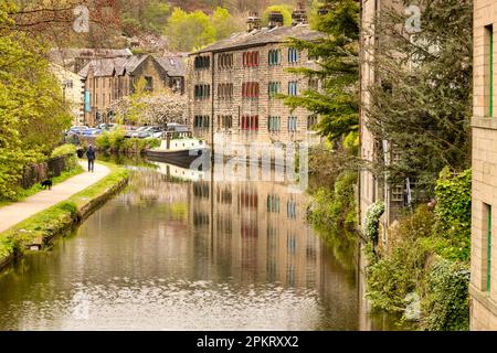 27. April 2022 - Hebden Bridge, West Yorkshire, Großbritannien - Ein Blick entlang des Kanals an der Hebden Bridge im Frühling. Eine Person führt einen Hund auf dem Abschleppweg. Stockfoto