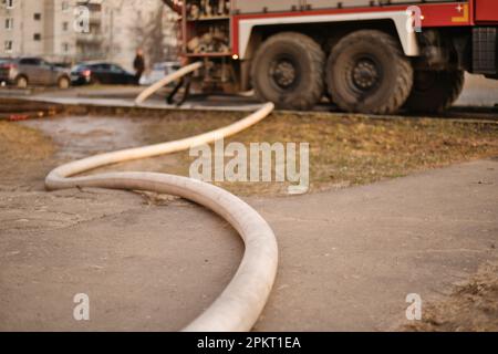 Feuerwehrschlauch am Boden angeschlossen in Feuerwehrwagen. Ein Feuer in der Stadt zu löschen. Selektiver Fokus. Stockfoto