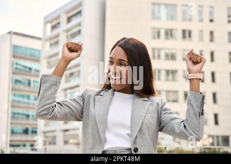 Aufgeregte junge afroamerikanische Geschäftsfrau feiert Erfolg beim Siegestanz Stockfoto