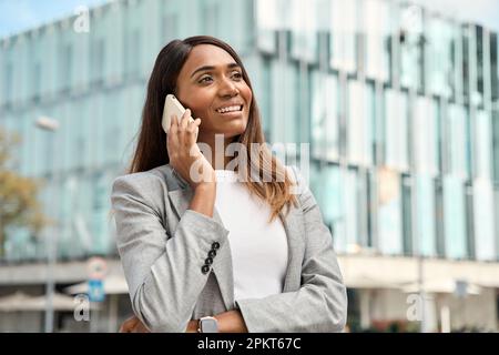 Fröhliches Porträt einer afroamerikanischen Geschäftsfrau, die draußen telefoniert. Stockfoto