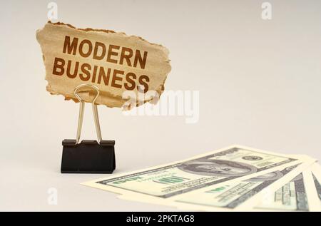 Geschäfts- und Finanzkonzept. Auf dem Tisch liegt Geld, daneben steht ein Pappschild mit der Aufschrift "Modern Business" Stockfoto