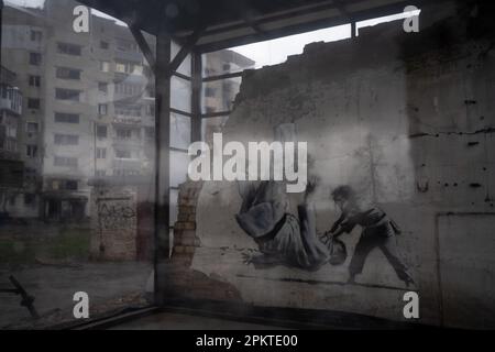 Borodyanka, Ukraine. 6. April 2023. Ein Wandbild des weltberühmten Graffiti-Künstlers Banksy ist in Borodyanka zu sehen. Der Mann auf dem Wandgemälde, der dem russischen Präsidenten Wladimir Putin ähnelt, der während eines Judo-Spiels mit einem Jungen umgedreht wurde. Trotz der einjährigen Befreiung von Borodyanka, einer Stadt nordwestlich der ukrainischen Hauptstadt Kiew, sind die Bewohner von Borodyanka nicht zur Normalität zurückgekehrt. Der Wiederaufbauprozess verlief stetig, aber langsam, zerstörte Gebäude bleiben im Stadtzentrum. Viele Bewohner haben in beschädigten Gebäuden gelebt, die jetzt teilweise repariert sind, während andere, die ihr Zuhause verloren haben, immer noch li sind Stockfoto