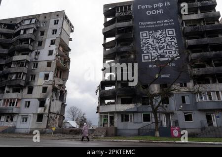 Borodyanka, Ukraine. 6. April 2023. Ein Einwohner von Borodyanka geht an einem zerstörten Gebäude vorbei, auf dem auf einem Plakat steht: „Kick Russia out the UN“. Trotz der einjährigen Befreiung von Borodyanka, einer Stadt nordwestlich der ukrainischen Hauptstadt Kiew, sind die Bewohner von Borodyanka nicht zur Normalität zurückgekehrt. Der Wiederaufbauprozess verlief stetig, aber langsam, zerstörte Gebäude bleiben im Stadtzentrum. Viele Bewohner leben in beschädigten Gebäuden, die jetzt teilweise repariert sind, während andere, die ihr Zuhause verloren haben, immer noch in provisorischen Wohnungen leben. Die Beamten sind sich noch nicht sicher, wann die Zeitlinie abgelaufen ist Stockfoto