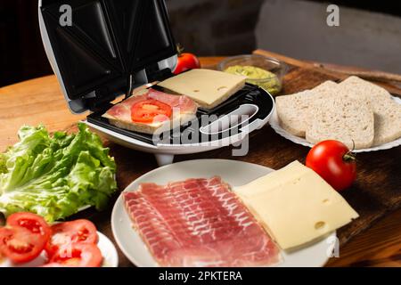 Sandwichmacher. Sandwiches mit verschiedenen Füllungen zubereiten. Stockfoto