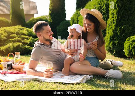 Glückliche Familie mit Picknick im Garten an sonnigen Tagen Stockfoto