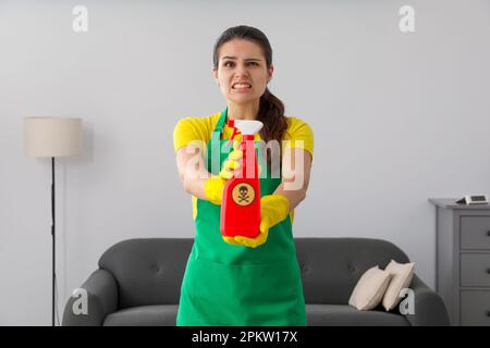 Frau, die eine Flasche giftiger Haushaltschemikalien mit einem Warnschild im Innenbereich vorführt Stockfoto