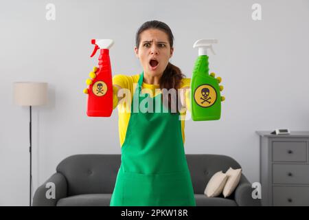 Eine Frau, die Flaschen mit giftigen Haushaltschemikalien mit Warnzeichen zeigt Stockfoto