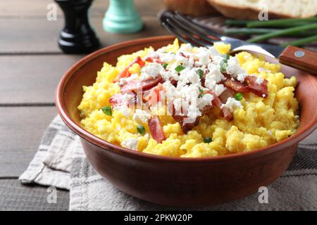 Leckerer Banosh serviert mit Brynza und Schweinegrieben in der Schüssel auf einem Holztisch, Nahaufnahme. Traditionelles ukrainisches Gericht Stockfoto