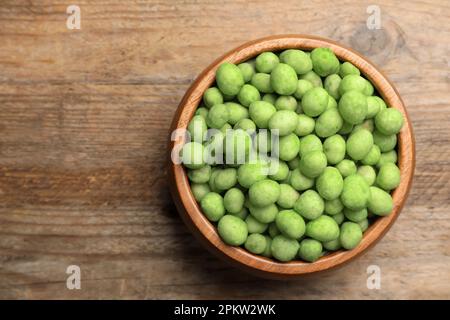 Leckere Wasabi-beschichtete Erdnüsse auf braunem Holztisch, Draufsicht. Platz für Text Stockfoto