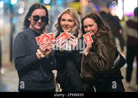 Broad Street, Birmingham, 10. April 2023 - drei Damen hatten einige kostenlose Shots für den Nachtclub Rosies gesammelt - Reveller auf der Broad Street in Birmingham wurden von starkem Wind und Regen getroffen, während sie die Nacht genossen und einen Feiertag folgen. Die Partygänger versteckten ihre Haare mit Mänteln und Handtaschen vor den Elementen, während die Dusche sich festhielt. Viele sahen viel kälter aus als in den vorherigen Nächten während der Feiertage. Eine Frau rutschte auf dem nassen Boden aus, fiel auf den Boden und Schnitt sich das Bein ab. Einige von denen trugen weiterhin Hasenohren, während Popworld einen menschengroßen Hasen hatte, der versuchte zu pp Stockfoto