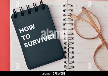 Notizbuch mit FRAGENHACKE ZUM ÜBERLEBEN geschrieben. Draufsicht. Stockfoto