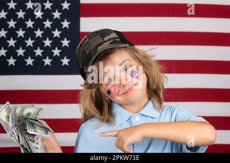 Amerikanisches Geld. Der Junge hat viele hundert Dollar isoliert im Studiohintergrund. Konzept der Vereinigten Staaten von Amerika. Zeichen der amerikanischen Flagge auf dem Kind Stockfoto