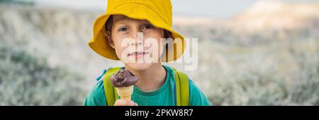 BANNER, LANGFORMAT Tourismusjunge, der türkisches Eis isst, während er das Tal mit Felsformationen und Feenhöhlen in der Nähe von Goreme in Kappadokien erkundet Stockfoto