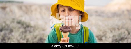 BANNER, LANGFORMAT Tourismusjunge, der türkisches Eis isst, während er das Tal mit Felsformationen und Feenhöhlen in der Nähe von Goreme in Kappadokien erkundet Stockfoto