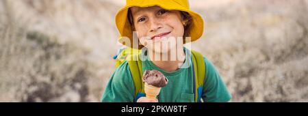 BANNER, LANGFORMAT Tourismusjunge, der türkisches Eis isst, während er das Tal mit Felsformationen und Feenhöhlen in der Nähe von Goreme in Kappadokien erkundet Stockfoto