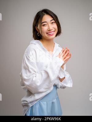 1/2 Half Body Porträt einer jungen asiatischen Frau in einem kurzen blauen Rock und einer weißen Langarmbluse | Weißer Hintergrund | Happy Stockfoto