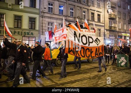 Breslau, Dolnoslaskie, Polen. 11. November 2014. Rechtsextreme Demonstranten aus der nationalen Wiedergeburt Polens halten die ultranationalistische politische Partei während des Protests für ihr Banner. Am 11. November findet der Polnische Unabhängigkeitstag statt, der große Unabhängigkeitsmarsch. Die Demonstranten fordern eine Rückkehr zu den traditionellen polnischen Werten und Identität und berufen sich dabei oft auf Katholizismus und Nationalismus als wichtige Teile ihrer Weltsicht. Viele von ihnen schließen sich rechtsextremen politischen Ideologien an und sind mit Organisationen wie der Nationalen Wiedergeburt Polens und der Allpolnischen Jugend und Fußball-Hooligans verbunden Stockfoto