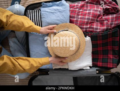 Eine Frau, die zu Hause Koffer packt, Draufsicht. Koffer mit Sachen gepackt. Reisekonzept Stockfoto