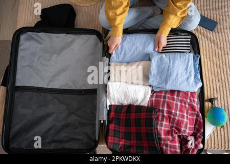 Eine Frau, die zu Hause Koffer packt, Nahaufnahme. Draufsicht. Reisekonzept Stockfoto