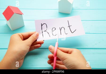 Das Wort "Rent" steht auf Papier und wird mit einer Schere in zwei Hälften geschnitten. Draufsicht Stockfoto