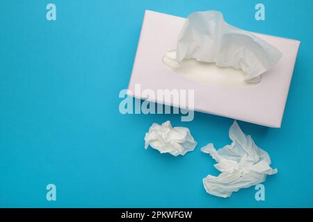 Karton mit Papiertüchern auf blauem Hintergrund. Draufsicht Stockfoto