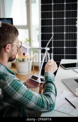 Enthusiast für grüne Energie, der ein kleines Modell einer für das Projekt entwickelten Windturbine prüft Stockfoto