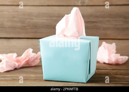 Blaue Box mit Papiertüchern und gebrauchten zerbrochenen Servietten auf grauem Holzhintergrund. Draufsicht Stockfoto