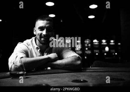 Junger Mann spielt Blackjack Behind Table im Casino Stockfoto