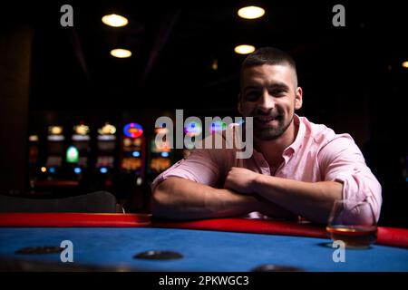 Junger Mann spielt Blackjack Behind Table im Casino Stockfoto