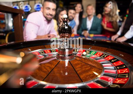 Drei Paare spielen nachts am Roulette Table in a Casino – Selektive Konzentration auf Roulette Stockfoto