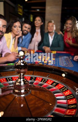 Drei Paare spielen nachts am Roulette Table in a Casino – Selektive Konzentration auf Roulette Stockfoto