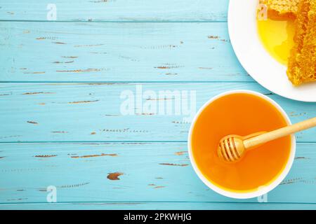 Schüssel mit Honig mit Wabenmuster auf blauem Holztisch. Draufsicht Stockfoto