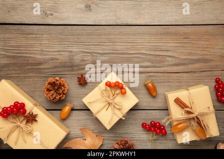 Geschenke mit Herbstviburnum, Kiefernzapfen und Eichel auf grauem Holzhintergrund. Herbstzusammensetzung. Draufsicht, flach liegend. Stockfoto