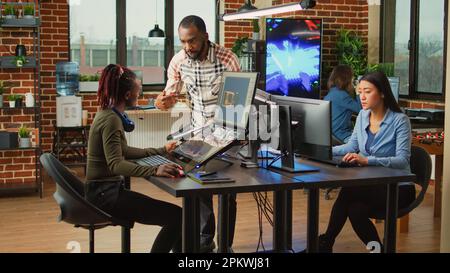 Kreative Content-Ersteller, die mit der künstlerischen Entwicklungsbranche zusammenarbeiten und mehrere Monitore auf dem Schreibtisch verwenden. Team von Mitarbeitern der Produktionsabteilung, die künstliche Intelligenz entwickeln. Stockfoto